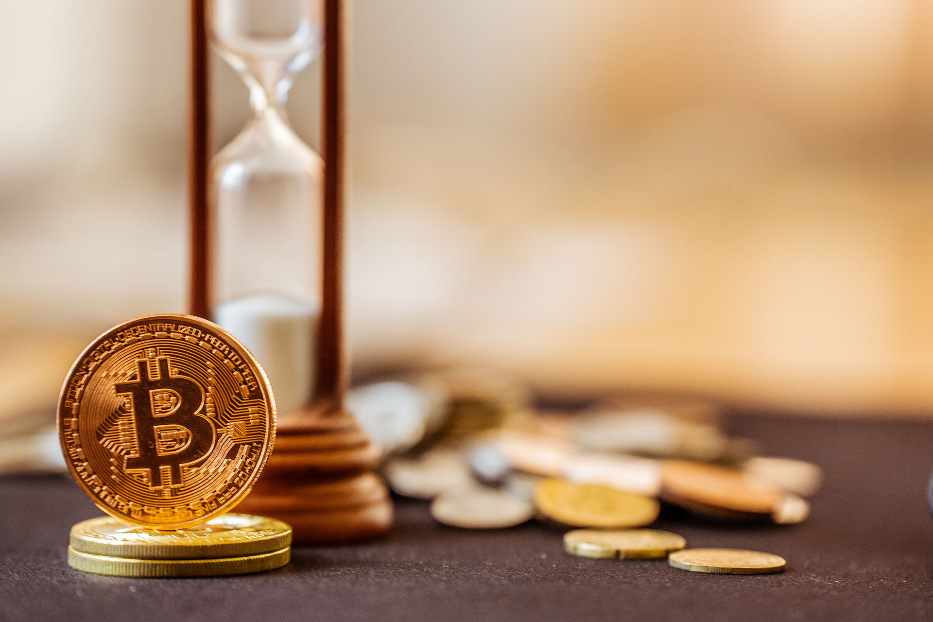 A Bitcoin coin standing beside an hourglass, illustrating time-based crypto savings returns